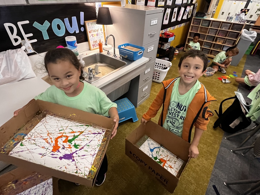 students smiling at the camera doing an art project