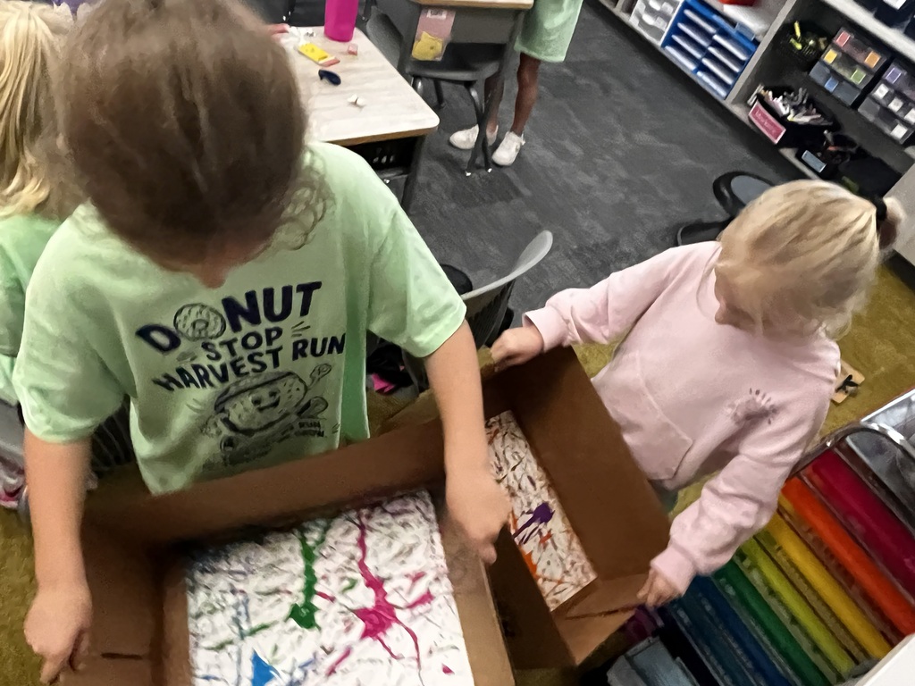 students are using marbles for painting in cardboard boxes