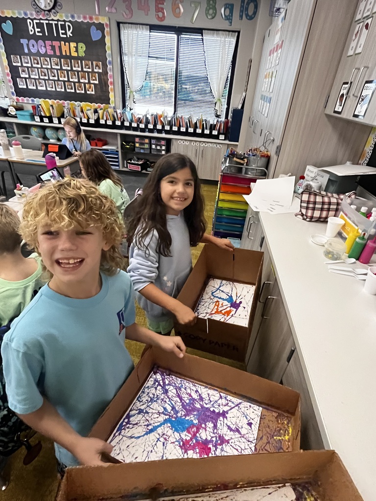 students are using marble painting in cardboard boxes in a classroom