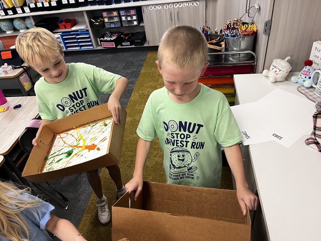 students working on a marble painting art project using white paper and cardboard boxes