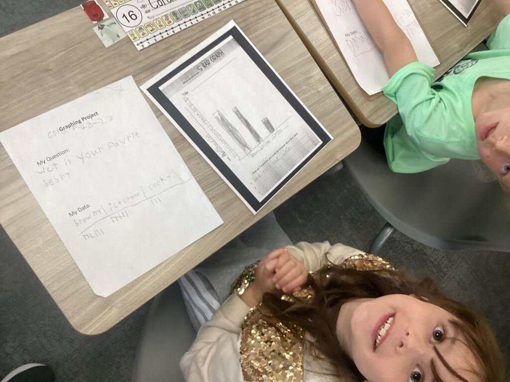 student working on a data sheet at their desk smiling at the camera