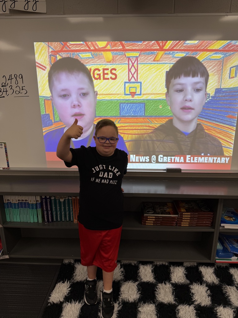 Student standing in front of a classroom with his thumb up in front of a projector screen