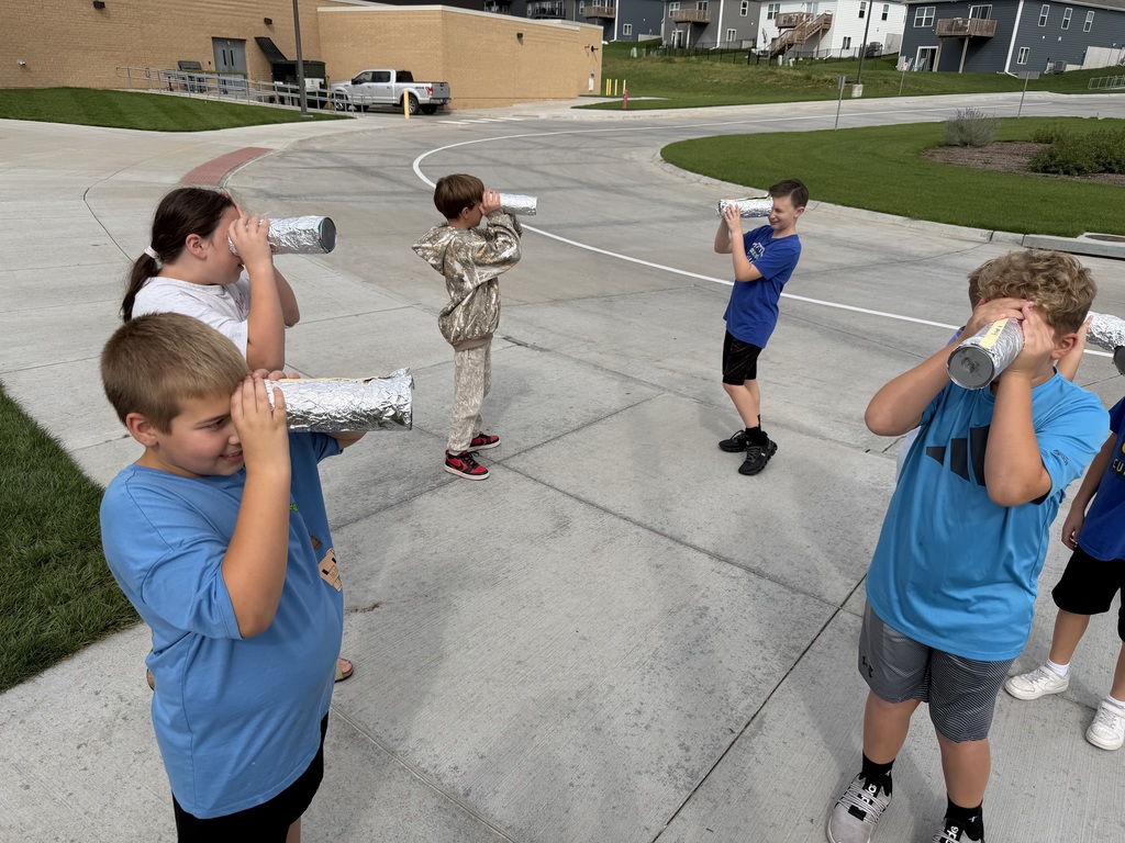 students looking through a pinhole camera outside in the bus loop