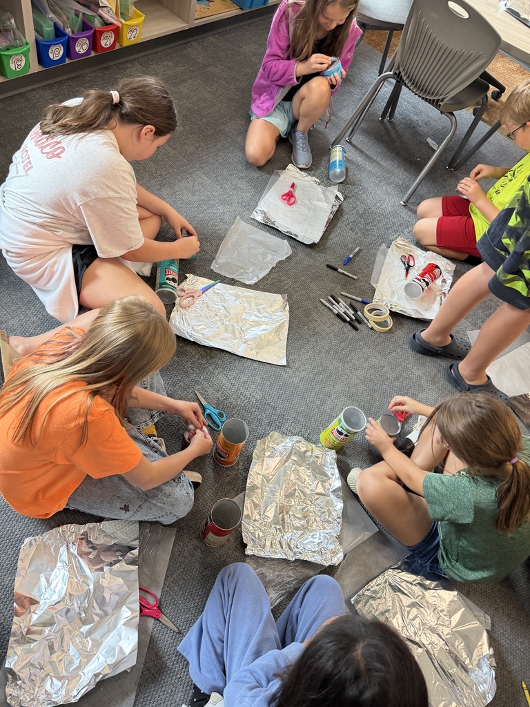 students working on a pinhole camera in their classroom with foil