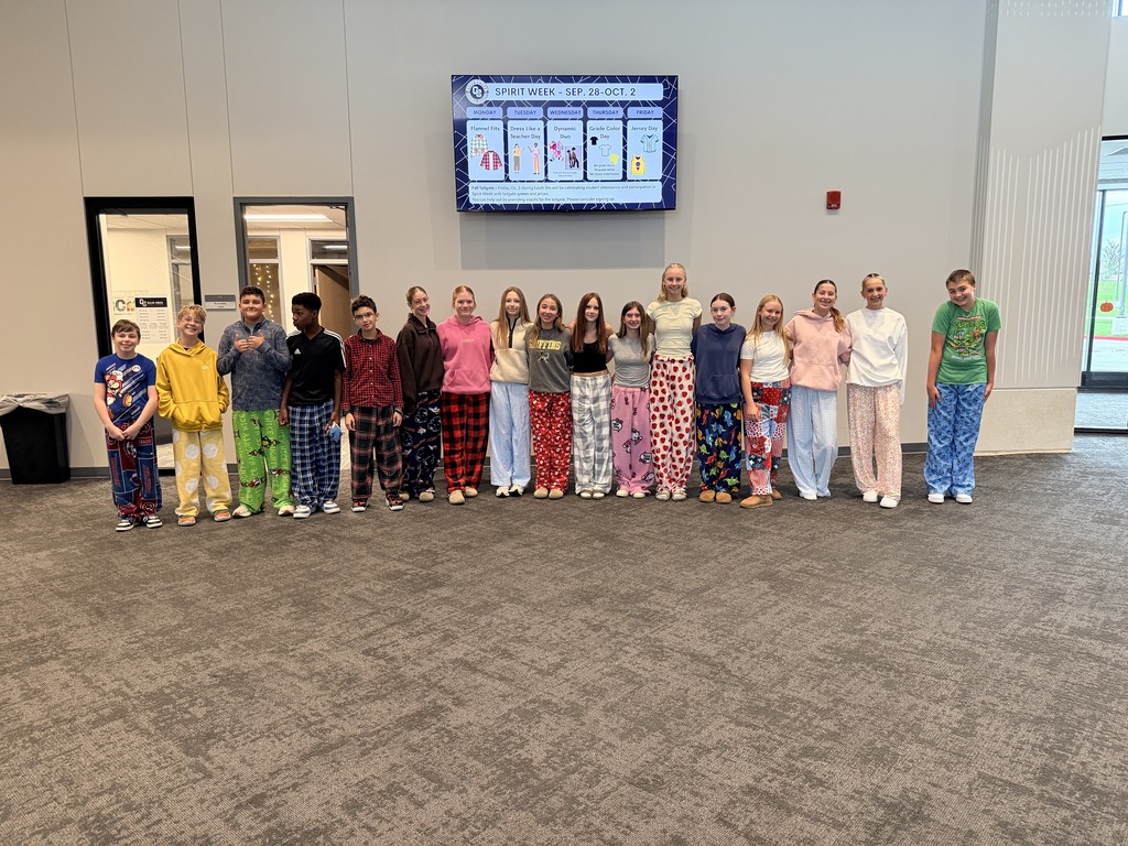 A group of students stands in front of a wall showing off their home made pajama pants. 