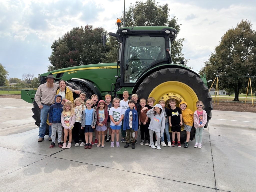 Group of children stand around a big green tractor with two adults