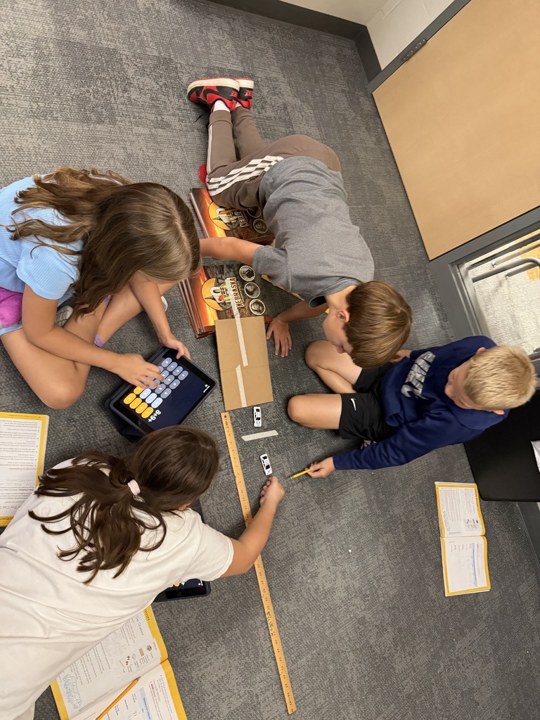 students measuring speed and velocity with books and yardsticks