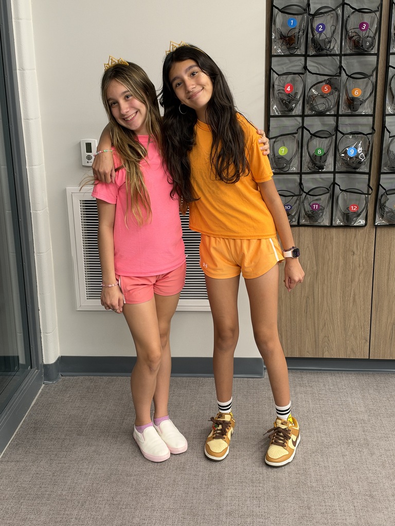 Two girls in matching outfits smile at the camera. 
