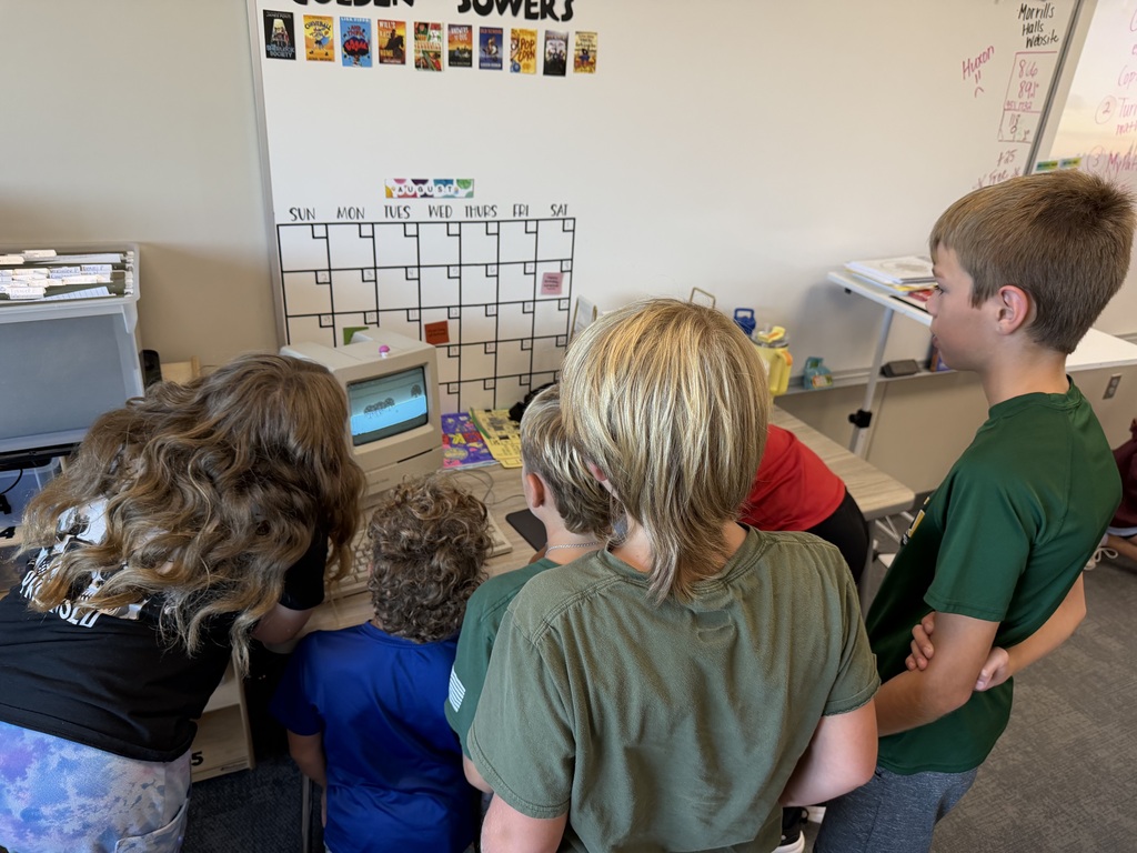 students hovered around an old macintosh computer