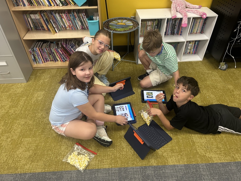 students sitting on the group sharing their work on ipads