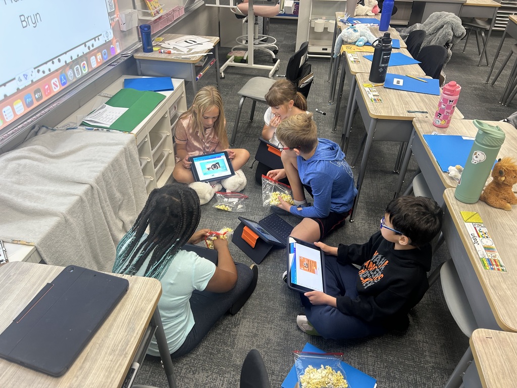 students sitting on the floor of their classroom in a circle sharing work