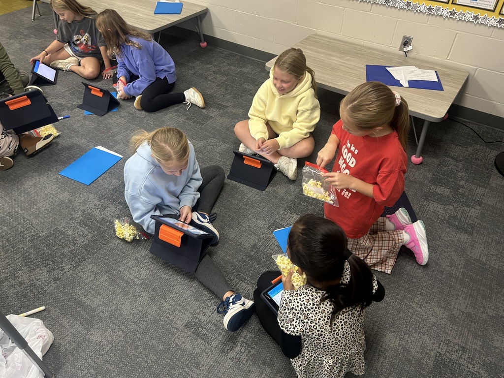 students sharing work on the floor of their classroom