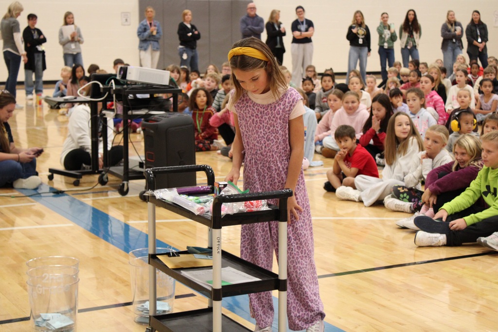 A second grade girl selects a prize from a cart.