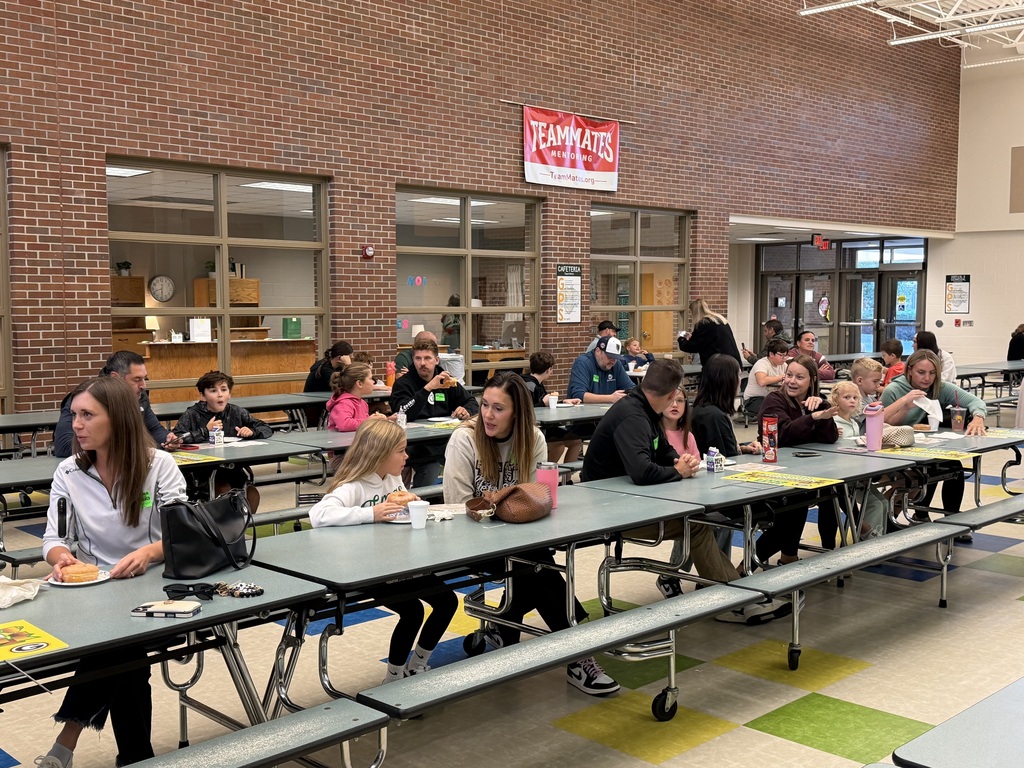 Students and their grown ups enjoying donuts. 
