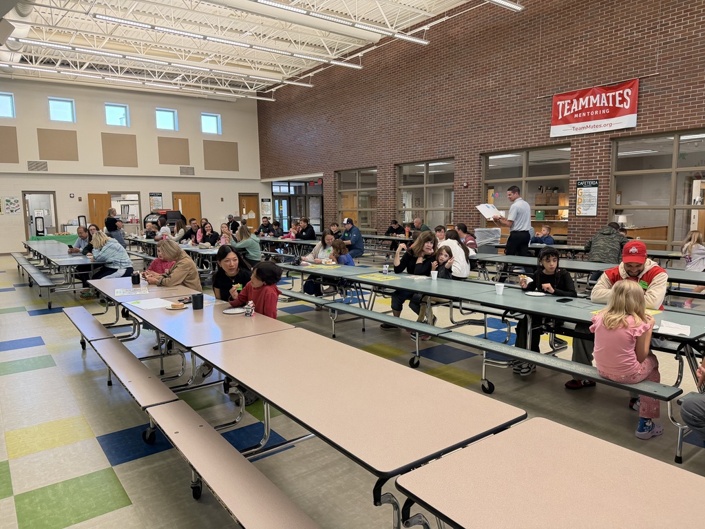 Students and their grown ups enjoying their donuts.