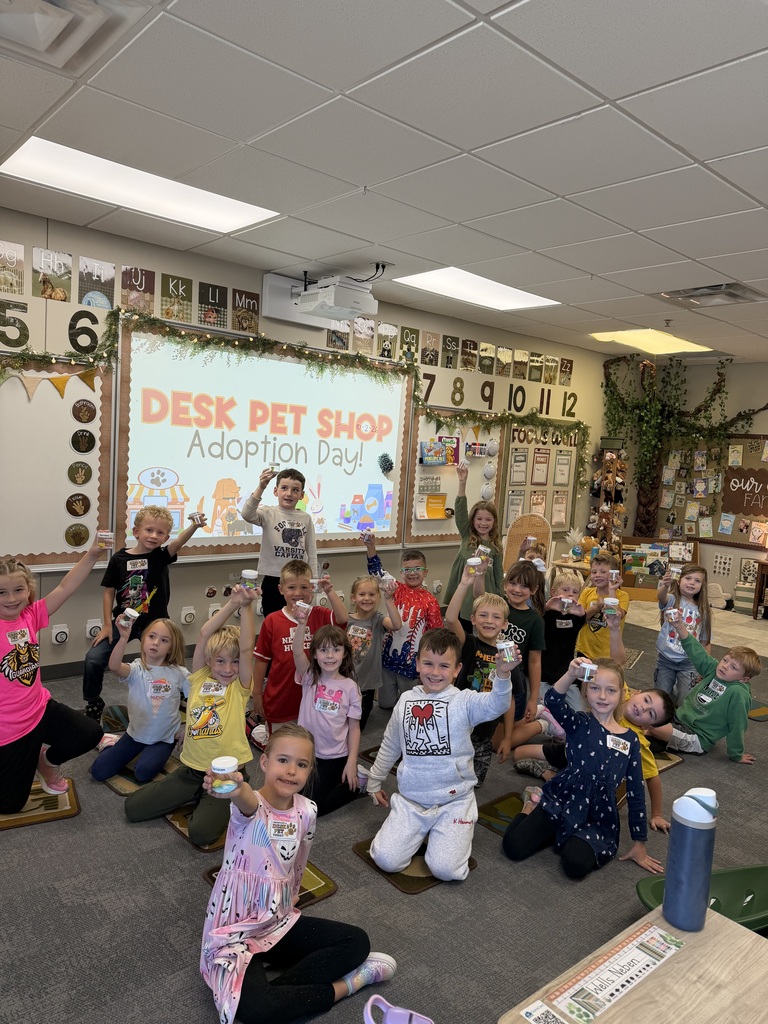 students in a classroom holding up their desk pets