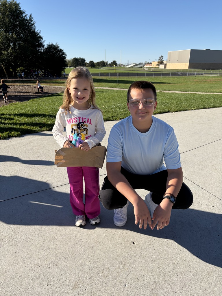A young girl in a long-sleeve "Mystical" shirt next to a boy in a light blue shirt squatting on the pavement.