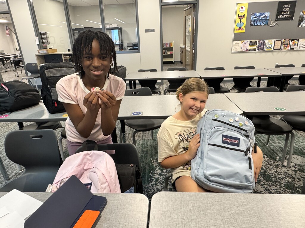 Two female students show off the buttons they made. 