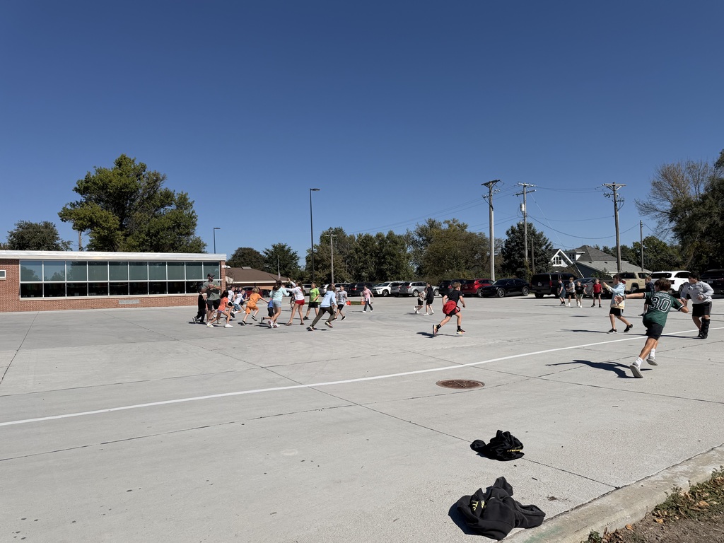 Another wide-angle shot of children participating in an outdoor football activity on the concrete playground area.
