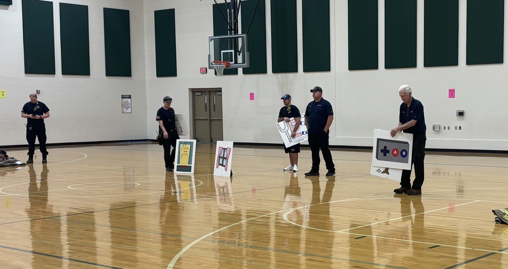 Firefighters standing on the gym floor during assembly. 