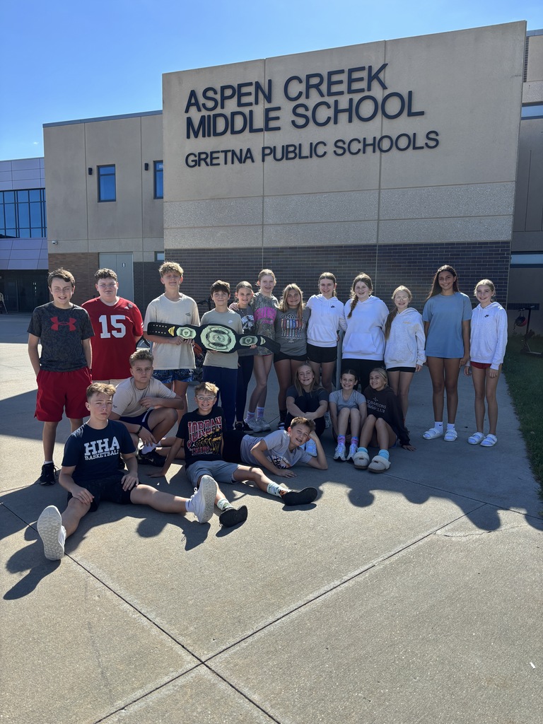 18 students outside of ACMS posing with Win the Moment belt award