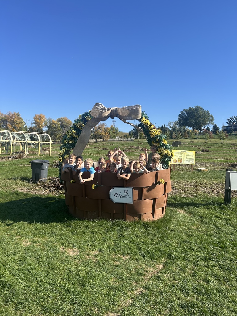 Large group of children posing together inside a giant decorative basket woven with a burlap bow and yellow sunflowers at Nelson Produce Farm.
