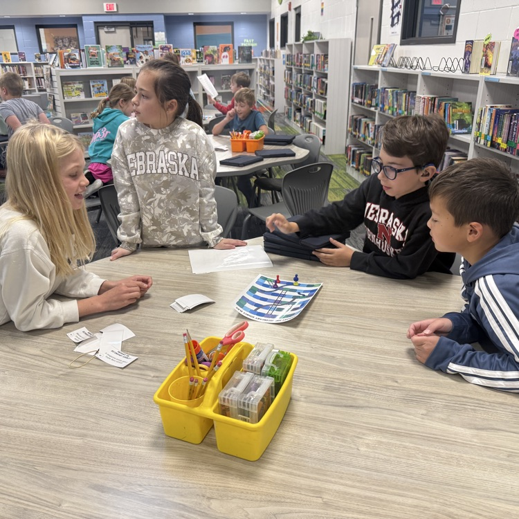 two third grade girls and two boys are playing a board game 