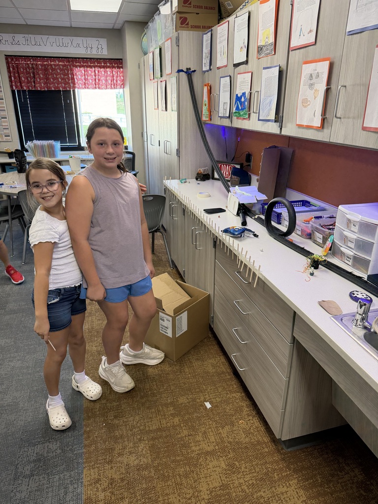 students pose by a track created in science class