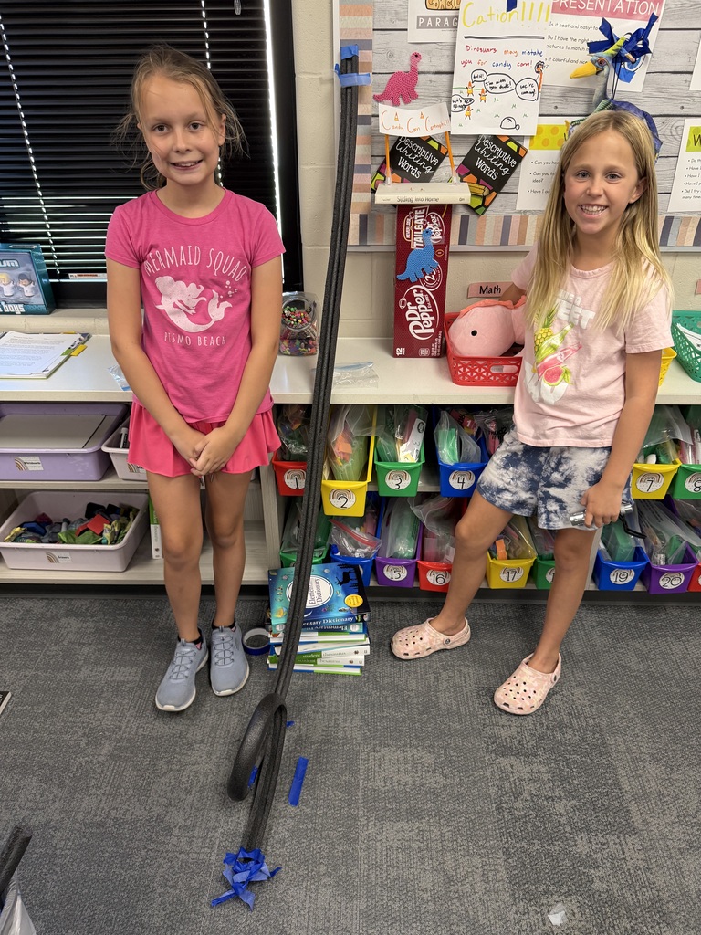 students pose by a track created in a classroom for science