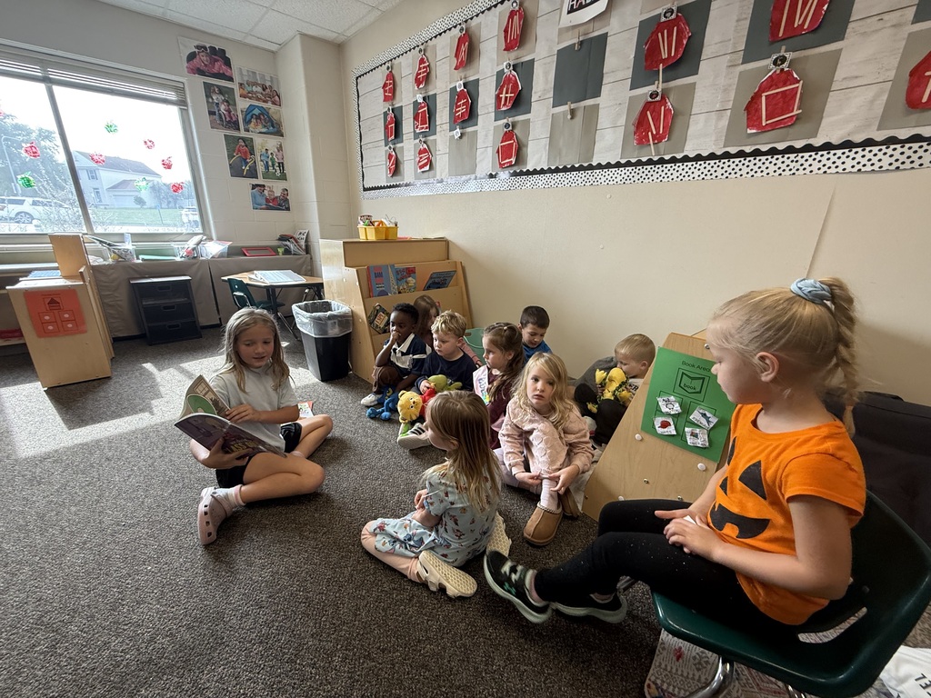 3rd grade student reading to group of preschool students
