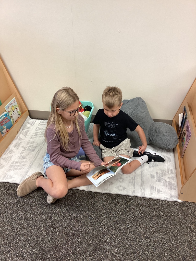 3rd grade student reading to preschool student
