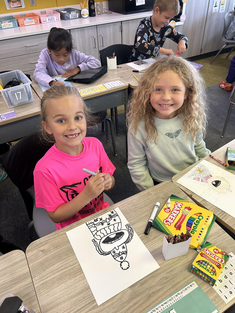 Students at their desk working on a buddy art project in a classroom.