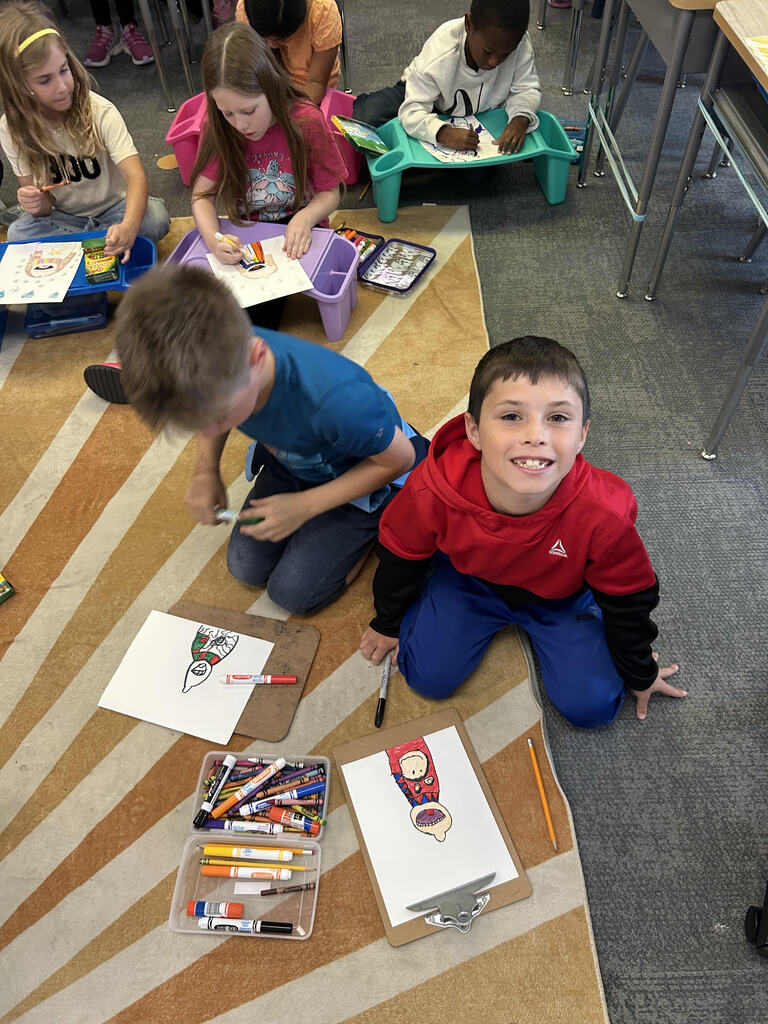 Students at their desk working on a buddy art project in a classroom.