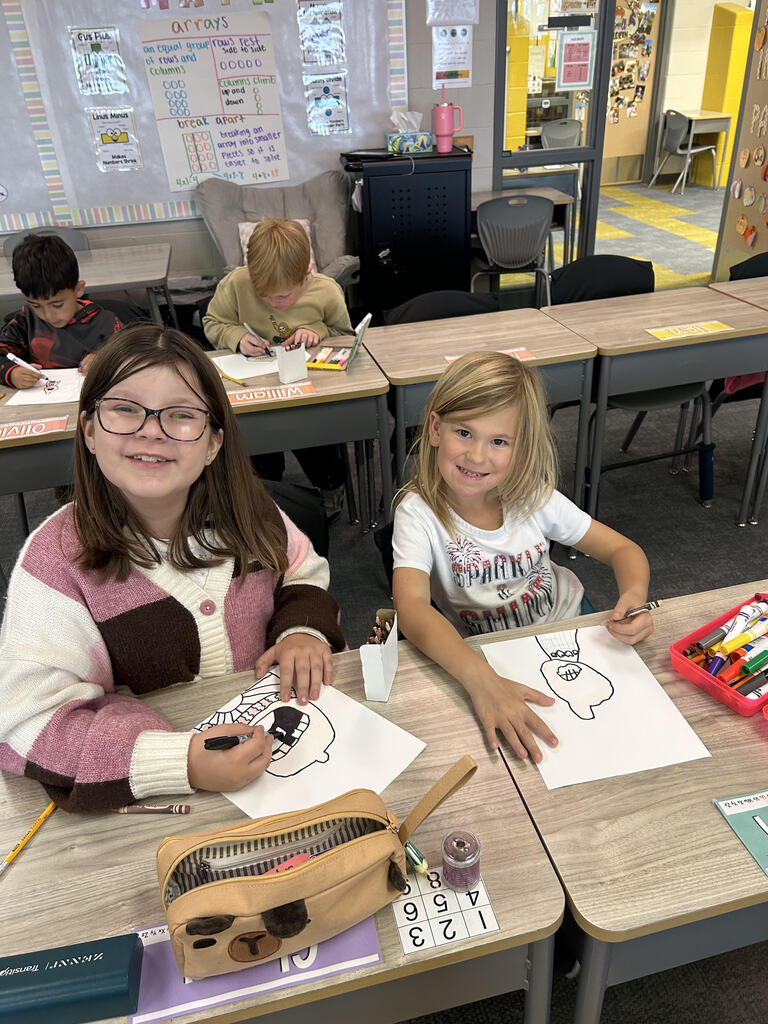 Students at their desk working on a buddy art project in a classroom.