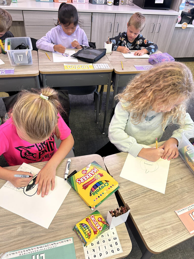 Students at their desk working on a buddy art project in a classroom.