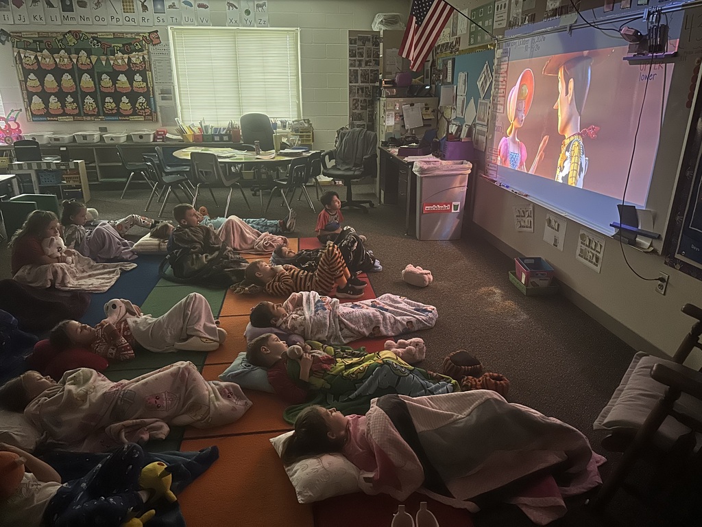 Students are laying with blankets watching a movie.