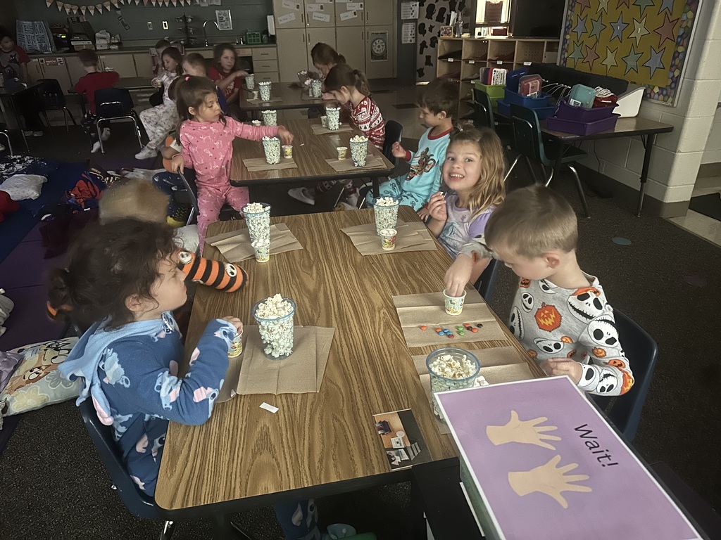 Students are eating popcorn, marshmallows, and M&Ms at tables.