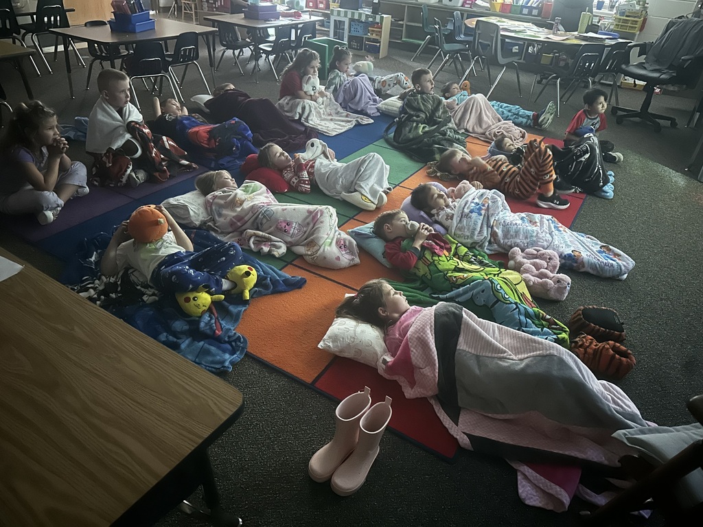 More students are laying with blankets watching a movie.