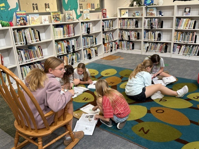 students on the floor of a library working on a research project