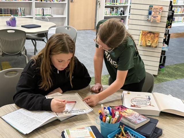 Two students working on a research project in a library class.