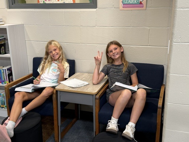students smiling while working on a research project together in chairs.