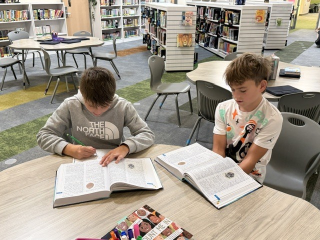 Two students in a library class with dictionaries