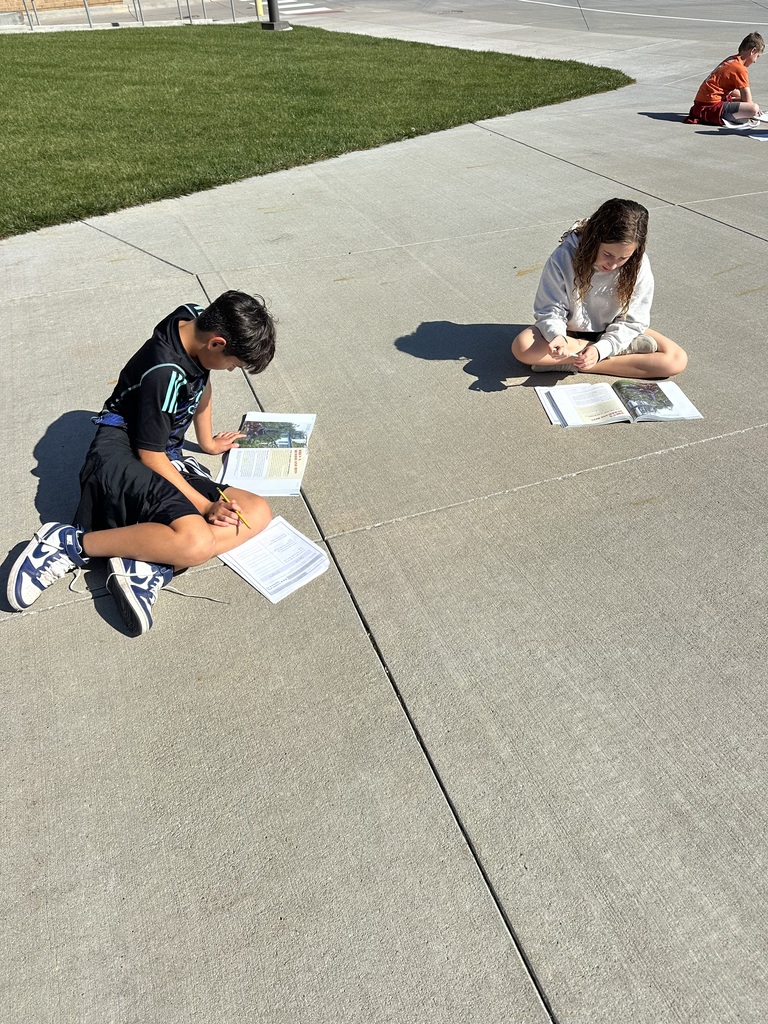 Harvest Hills students reading and learning outside on the pavement.