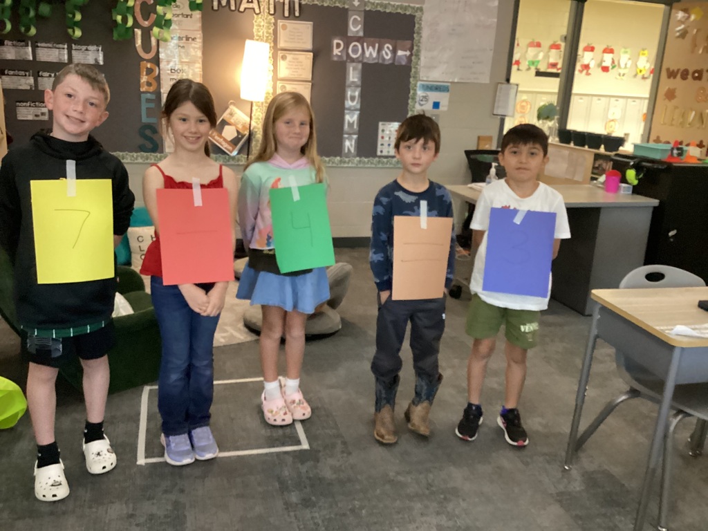 Students in Mrs. Collins' 2nd grade WIN group pose with numbers taped to their clothes for a fact family project in the classroom.