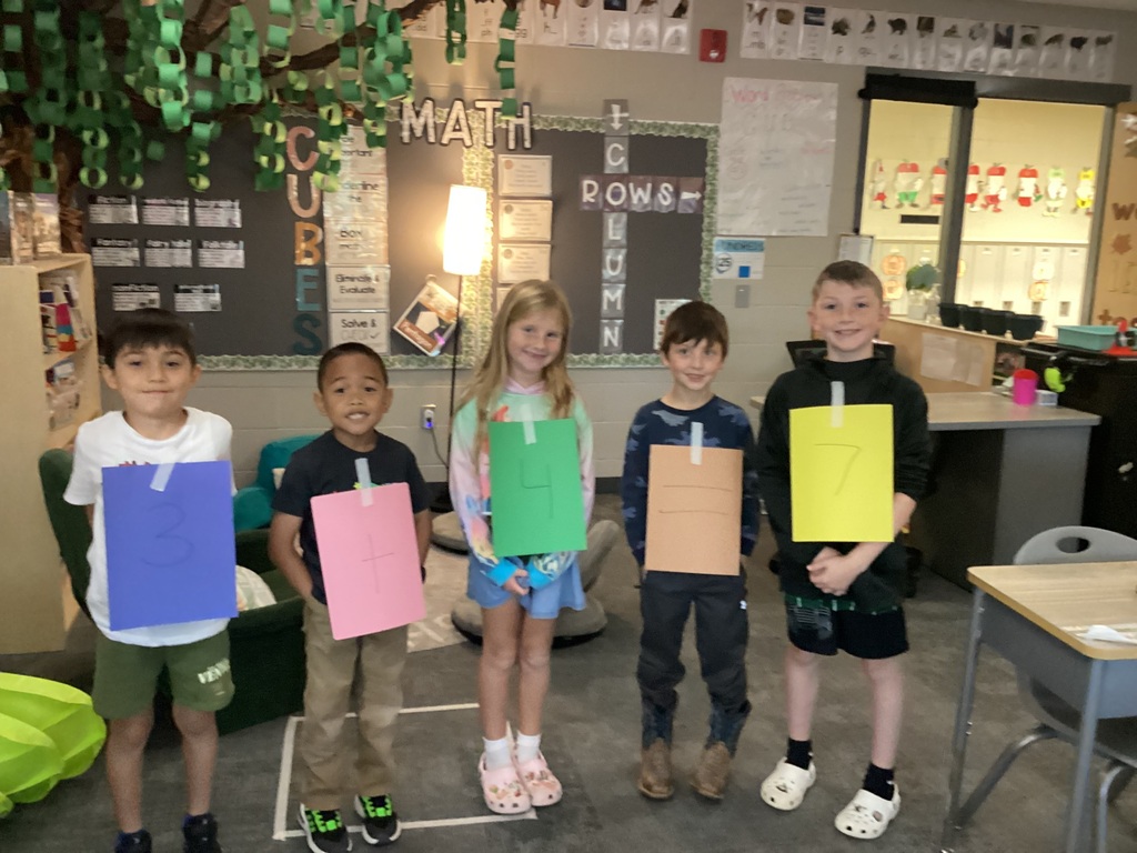 Students in Mrs. Collins' 2nd grade class pose with numbers taped to their clothes for a fact family project in the clasrrom.