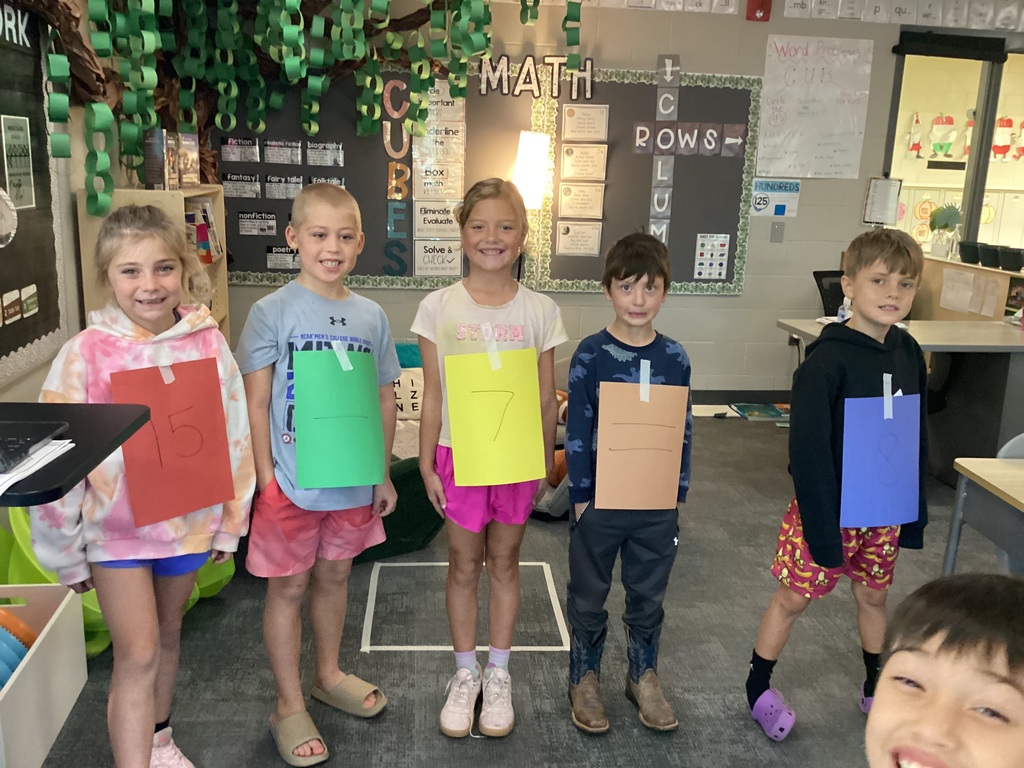 Students in Mrs. Collins' 2nd grade WIN group pose with numbers taped to their clothes for a fact family project in the classroom.