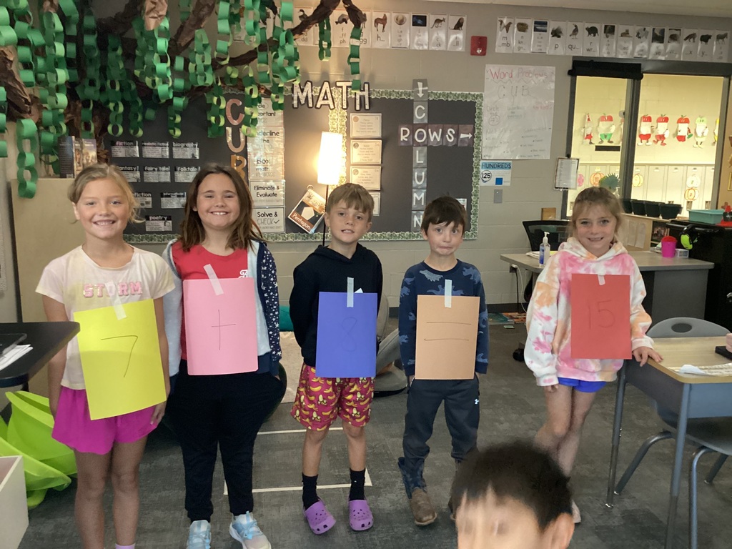 Students in Mrs. Collins' 2nd grade WIN group pose with numbers taped to their clothes for a fact family project in the classroom.