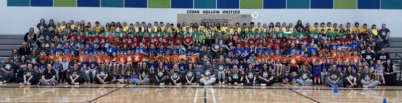 School photo sitting on the bleachers facing the camera in colorful shirts.