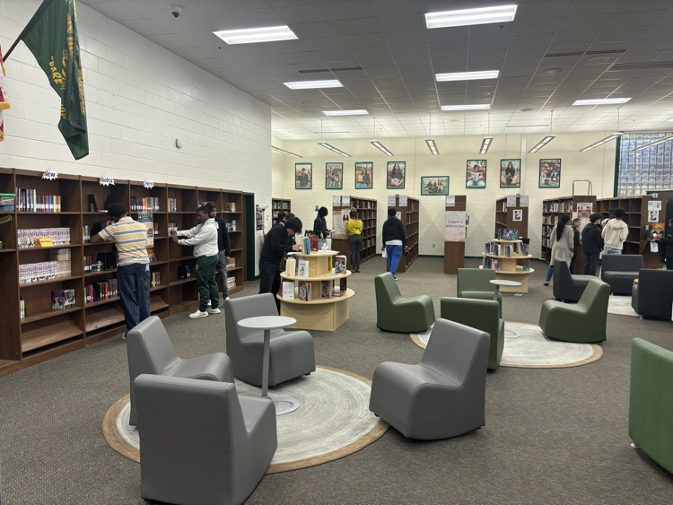 students moving around the media center taking notes and answering questions