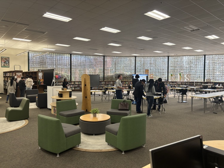 students moving around the media center taking notes and answering questions